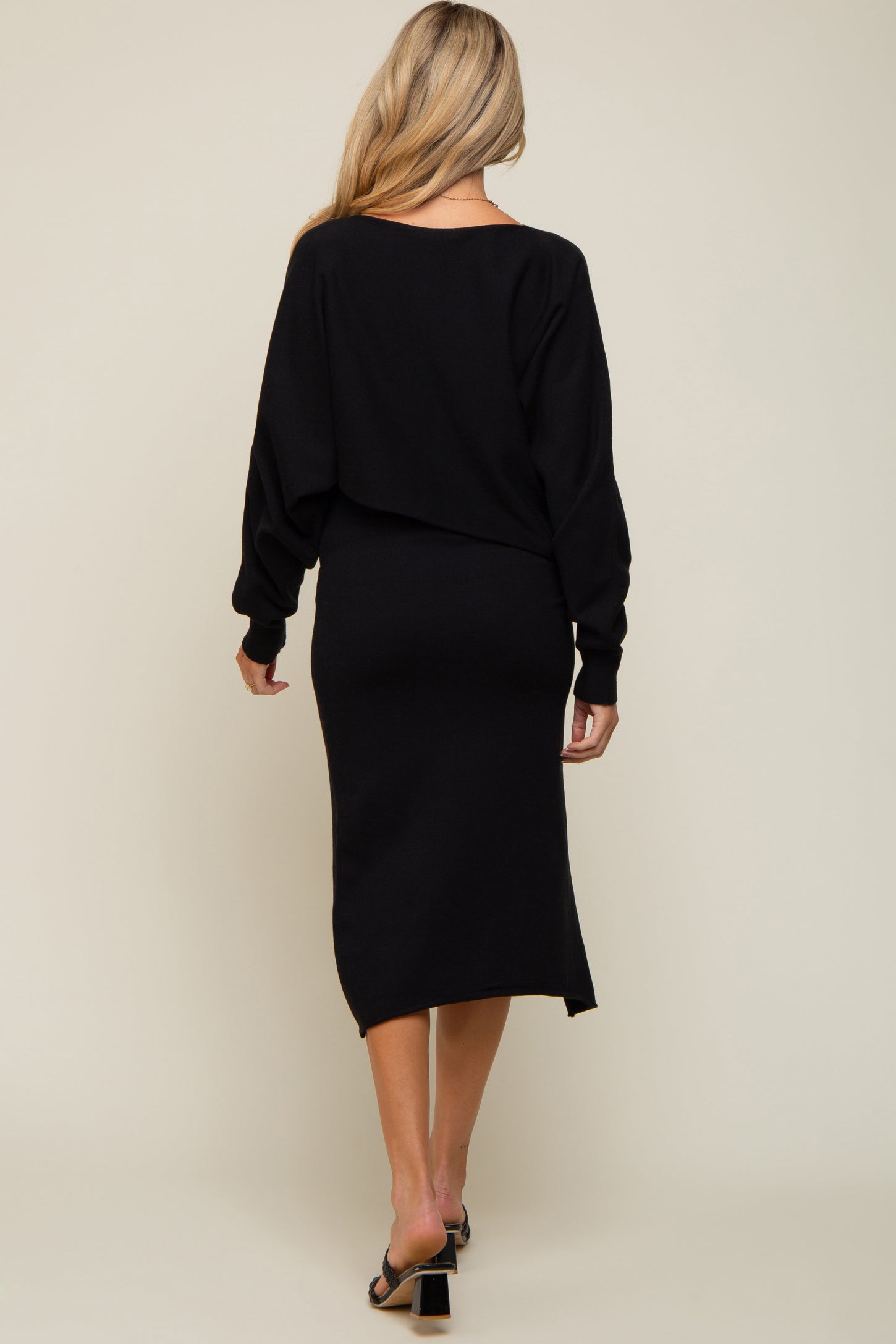 woman wearing a black maternity dress with a relaxed fit and long sleeves, showing a baby bump from the back