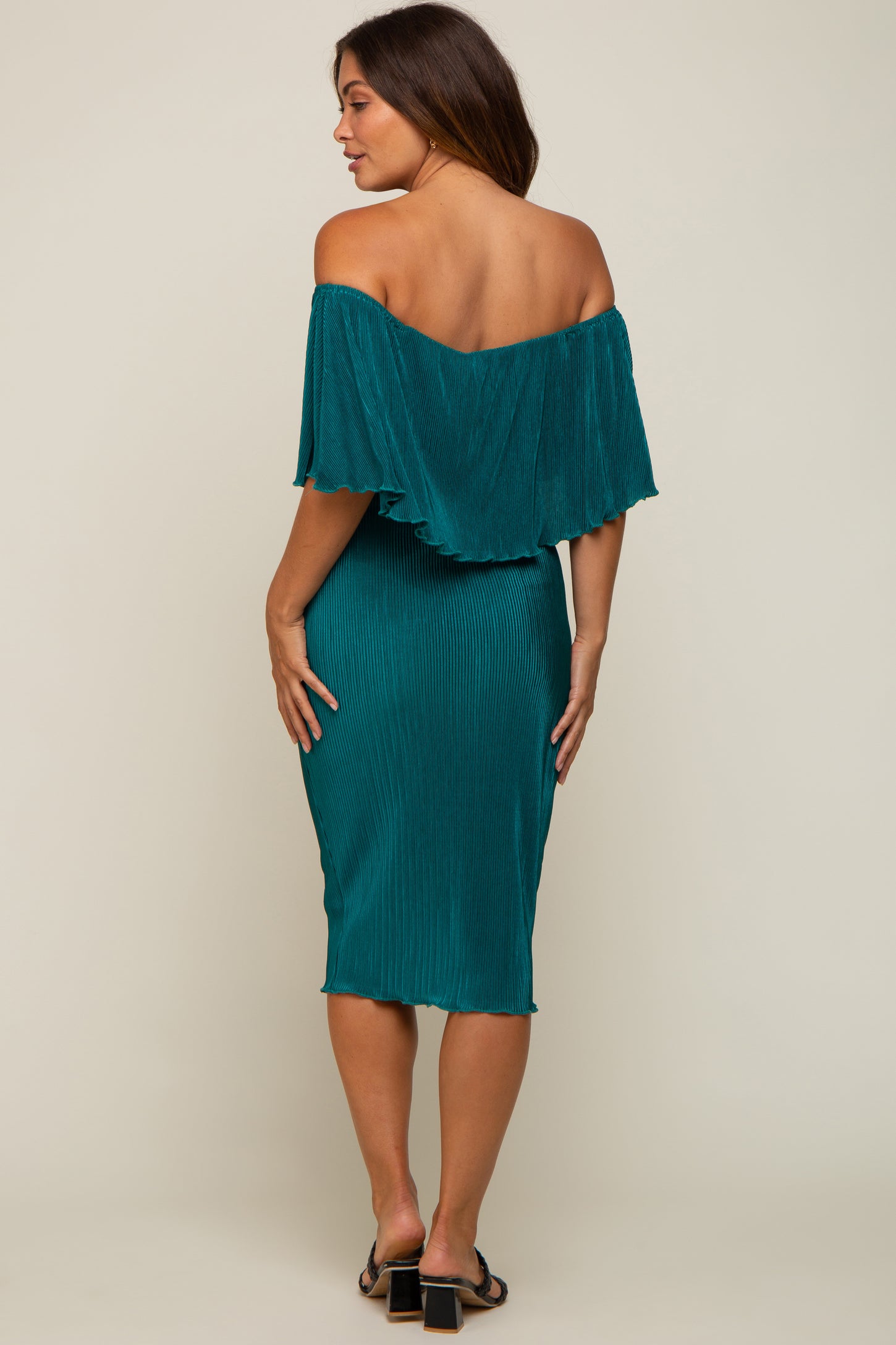 woman wearing a teal off-the-shoulder maternity dress with a fitted skirt and ruffled overlay