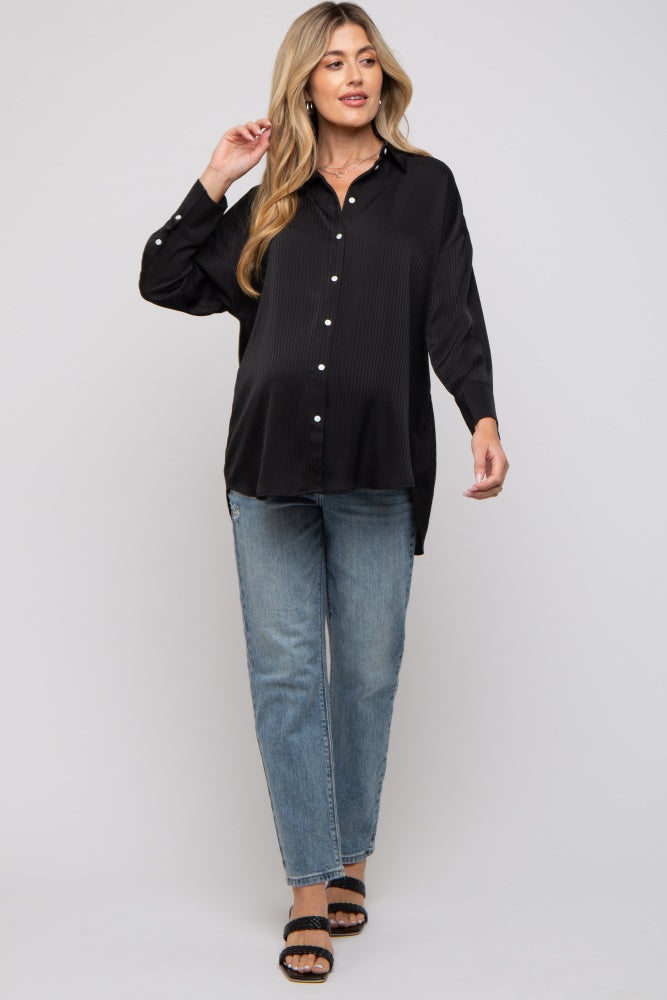 woman wearing a black long sleeve maternity shirt with buttons and blue jeans, showing her baby bump