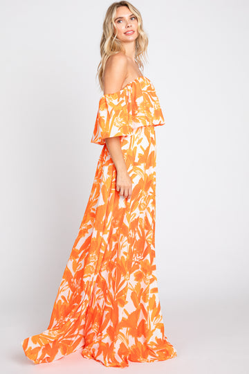 woman wearing an off-the-shoulder orange floral maxi dress standing sideways