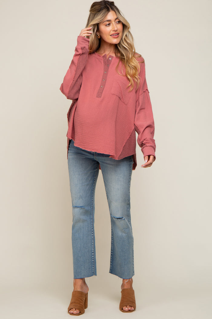 woman wearing a coral long sleeve waffle knit maternity top with buttons and pocket, paired with distressed light wash maternity jeans and heels