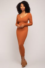 woman wearing a rust ribbed long sleeve midi dress with a V-neckline and a fitted silhouette