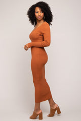 woman wearing a rust-colored ribbed knit midi dress with long sleeves and side slit, styled with nude block heel sandals