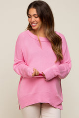 smiling woman wearing a pink oversized knit sweater with long sleeves and a round neckline