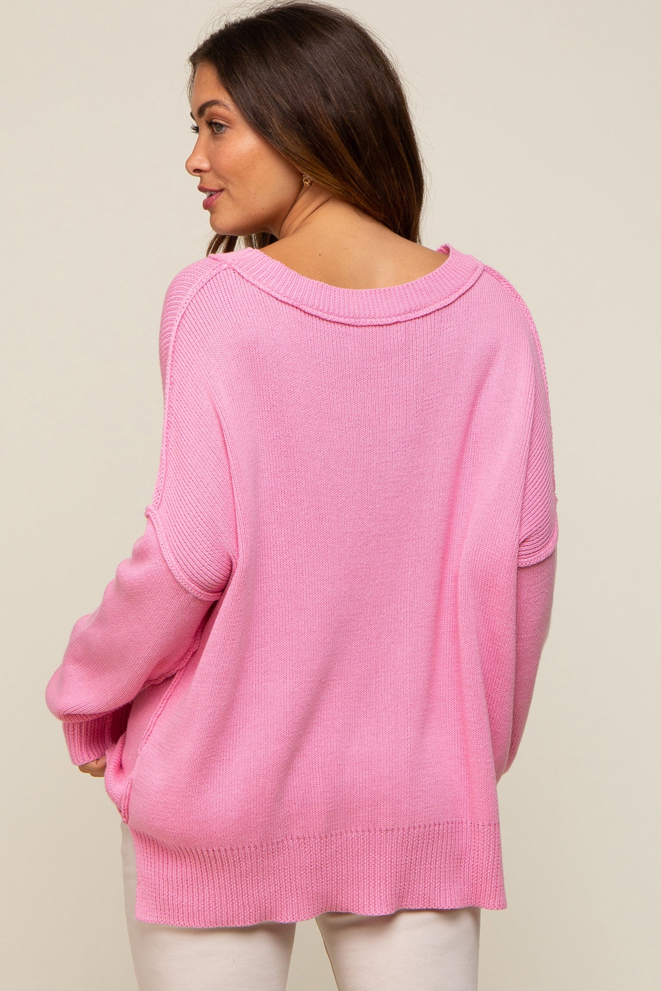 woman wearing a loose-fitting pink maternity sweater with a wide neckline and a relaxed fit from the back