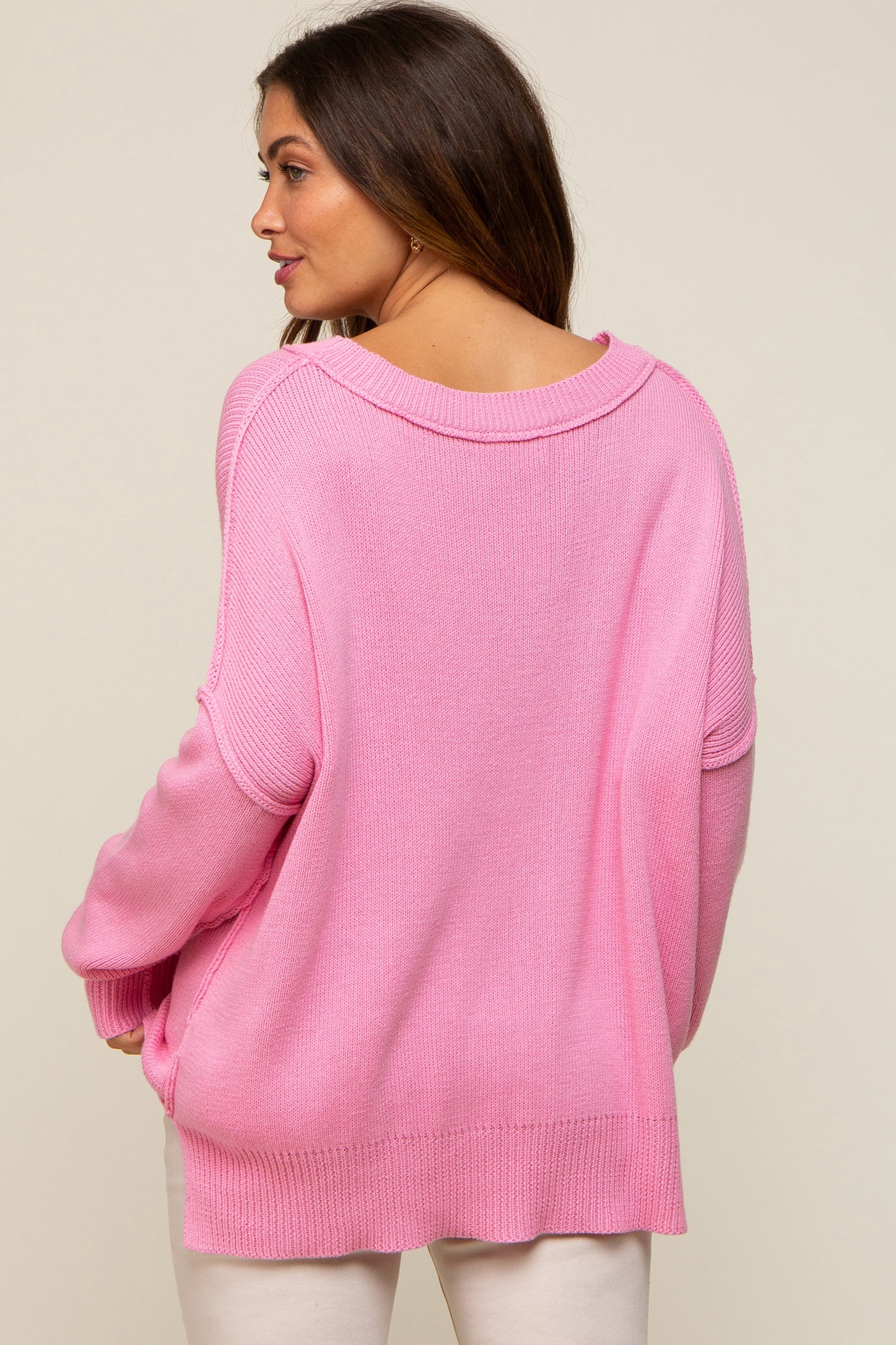 woman wearing a loose-fitting pink maternity sweater with a wide neckline and a relaxed fit from the back