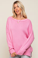 woman wearing a oversized pink knitted sweater with a wide neckline and side slits