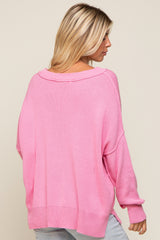 woman wearing a loose-fitting pink oversized sweater with a wide neckline and long sleeves