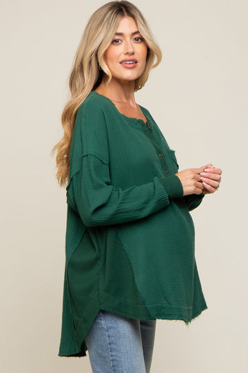 woman wearing a dark green maternity shirt with buttons and a relaxed fit, showcasing her baby bump