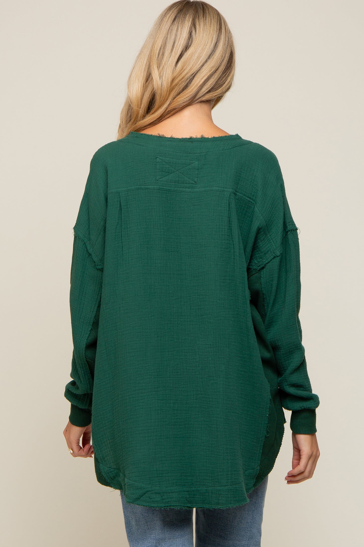 woman wearing a dark green maternity top with a relaxed fit and long sleeves, viewed from the back