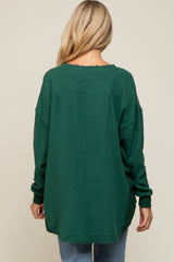 woman wearing a dark green maternity top with a relaxed fit and long sleeves, viewed from the back