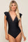 woman wearing a black one-piece swimsuit with ruffle sleeves and a deep v-neckline