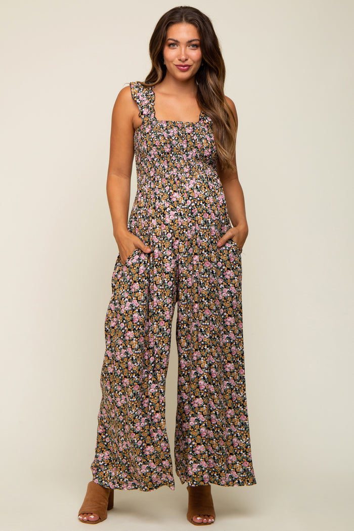 woman wearing a floral maternity jumpsuit with wide legs and pockets, featuring a square neckline and ruffled straps