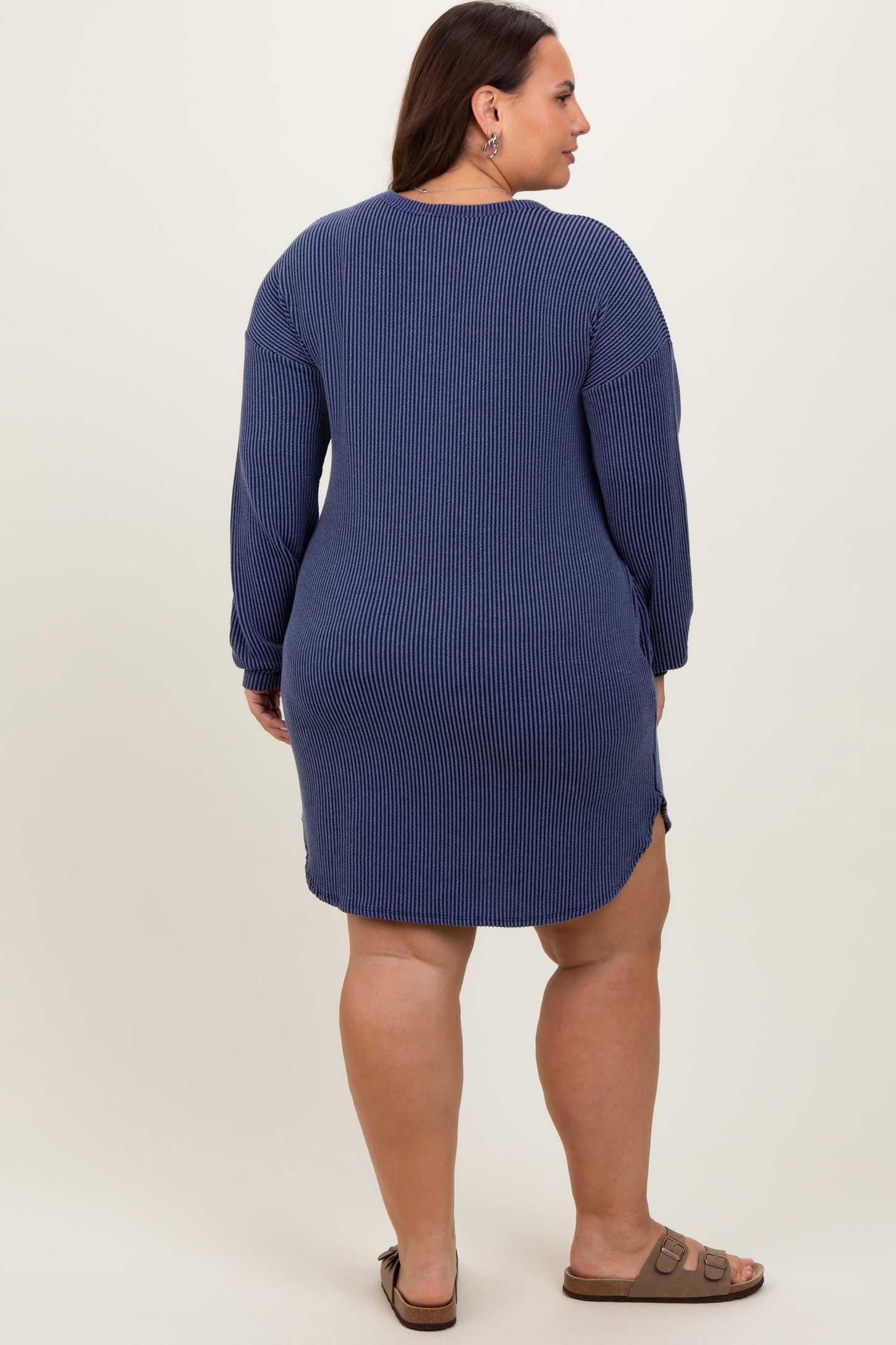 woman wearing a navy blue ribbed long sleeve dress with a relaxed fit and side slits, seen from the back
