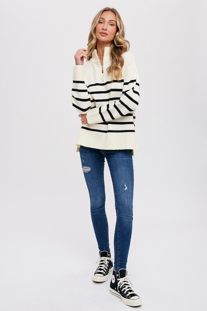 woman wearing cream and black striped quarter-zip sweater with distressed blue skinny jeans and high-top sneakers