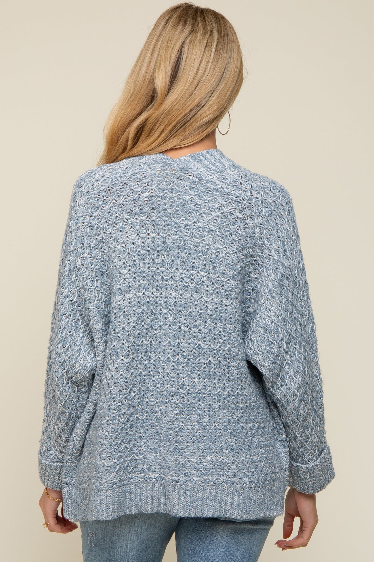 woman wearing a light blue knitted maternity sweater with a relaxed fit and long sleeves, seen from the back