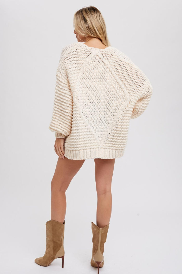 woman wearing an oversized cream colored sweater with textured knit and drop shoulders, showing the back view