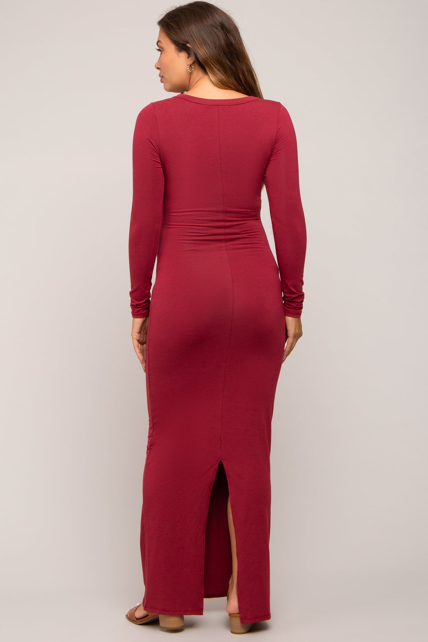 woman wearing a burgundy long sleeve maternity dress with a fitted style and a back slit