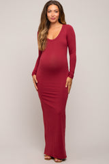 woman wearing a burgundy long sleeve maternity maxi dress with a visible baby bump