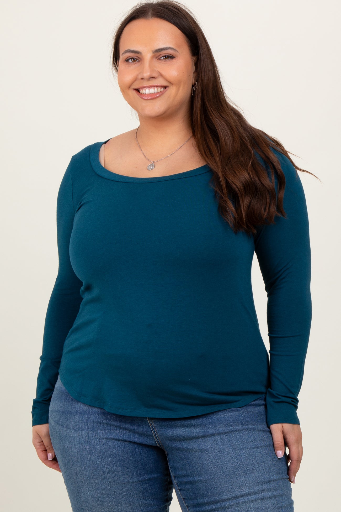 woman wearing a teal long sleeve top with a scoop neckline paired with blue jeans