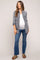 woman wearing a gray maternity button-up shirt over a white top and blue jeans, showing her baby bump