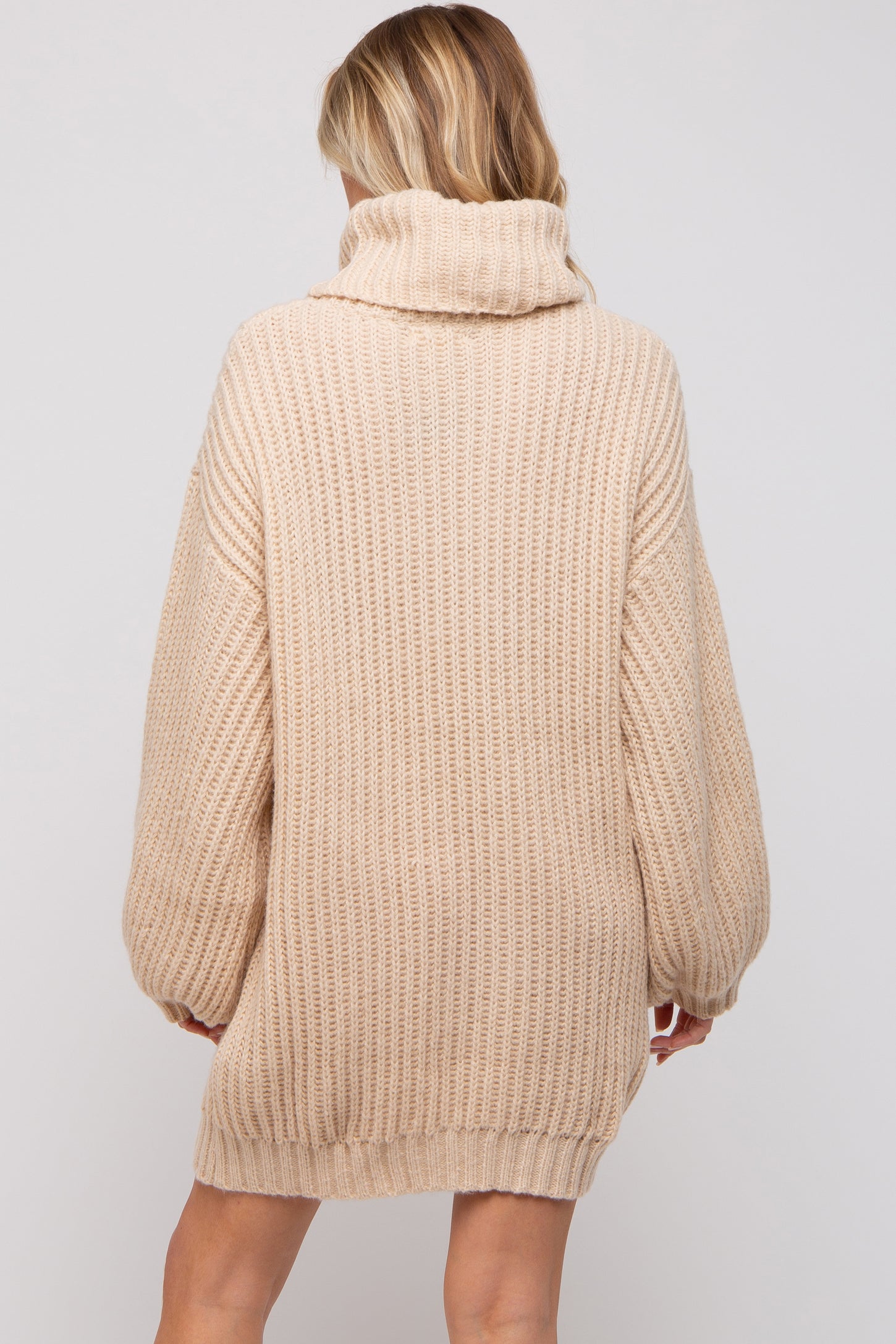 woman wearing a beige oversized ribbed maternity sweater with a cowl neck and long sleeves
