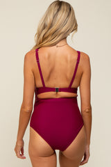 woman wearing a burgundy maternity swimsuit with adjustable straps and a cutout back