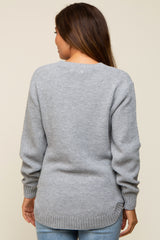 woman wearing a grey maternity sweater with a textured knit and longer back hem