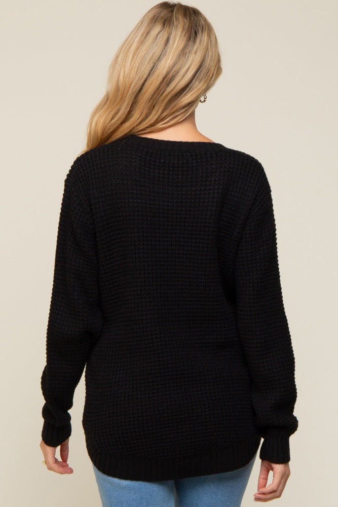 woman wearing a black knitted maternity sweater, with long sleeves and a relaxed fit, seen from the back