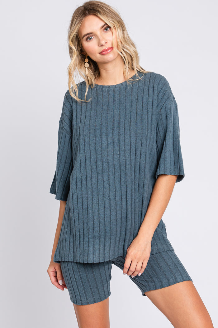 woman wearing a teal ribbed knit oversized top and matching shorts, styled casually with earrings