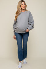 woman wearing a gray maternity sweatshirt and blue flared jeans, showing her baby bump, paired with white sneakers