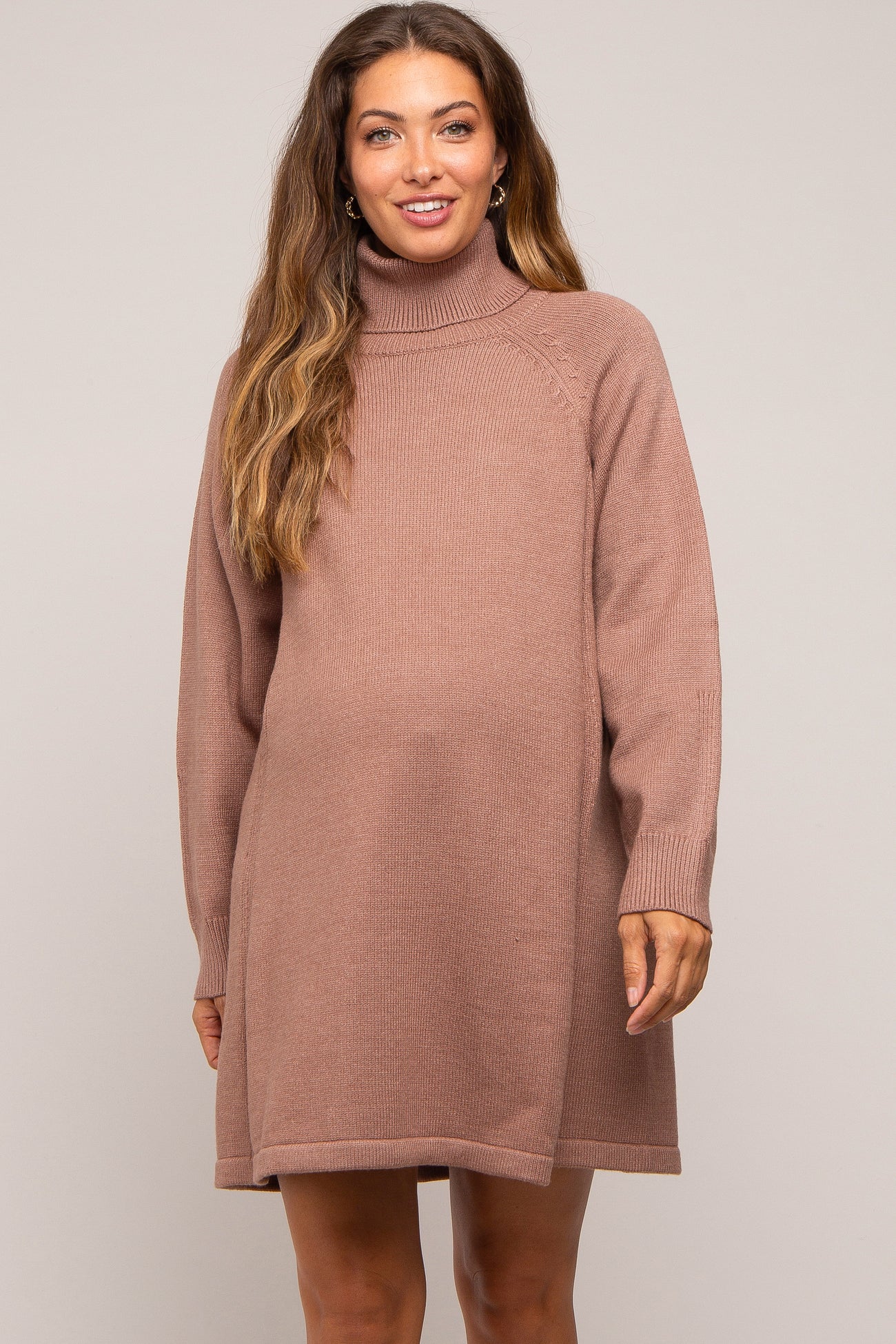 woman wearing a mauve turtleneck maternity dress with long sleeves and a relaxed fit, baby bump visible