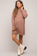 woman wearing a brown maternity turtleneck sweater dress with a visible baby bump and trendy white ankle boots