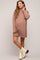 woman wearing a brown maternity turtleneck sweater dress with a visible baby bump and trendy white ankle boots