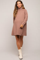 woman wearing a soft pink oversized maternity sweater dress with a turtleneck and a visible baby bump