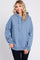 woman wearing a blue oversized hoodie with a drawstring and side slits, smiling at the camera