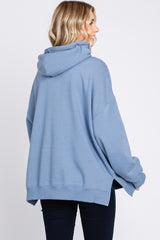 woman wearing a blue oversized hoodie with a high neckline and slouchy fit, viewed from the back