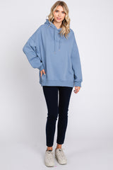 woman wearing a light blue oversized hoodie with a drawstring and black skinny jeans