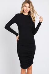 woman wearing a black long sleeve ribbed dress with ruched detailing along the sides