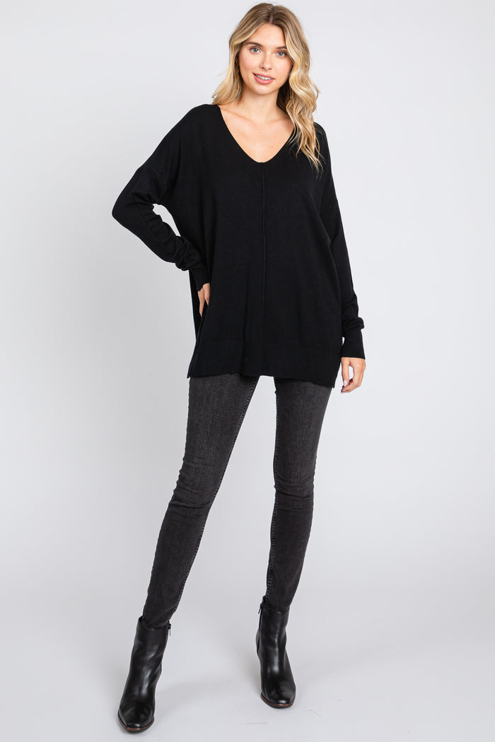 woman wearing a black loose fit v-neck sweater with long sleeves paired with dark skinny jeans and ankle boots