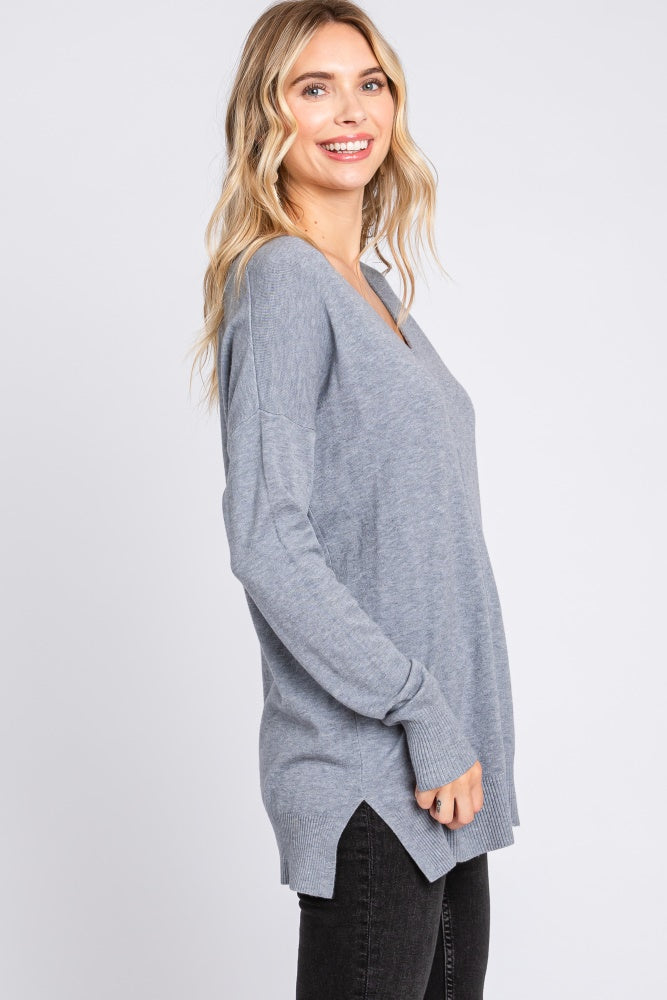 woman wearing a gray long sleeve v-neck sweater with side slits and a relaxed fit