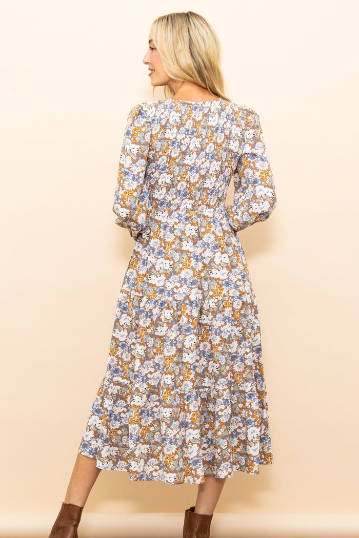woman wearing a floral long sleeve midi dress with a fitted bodice and flowing skirt, seen from the back