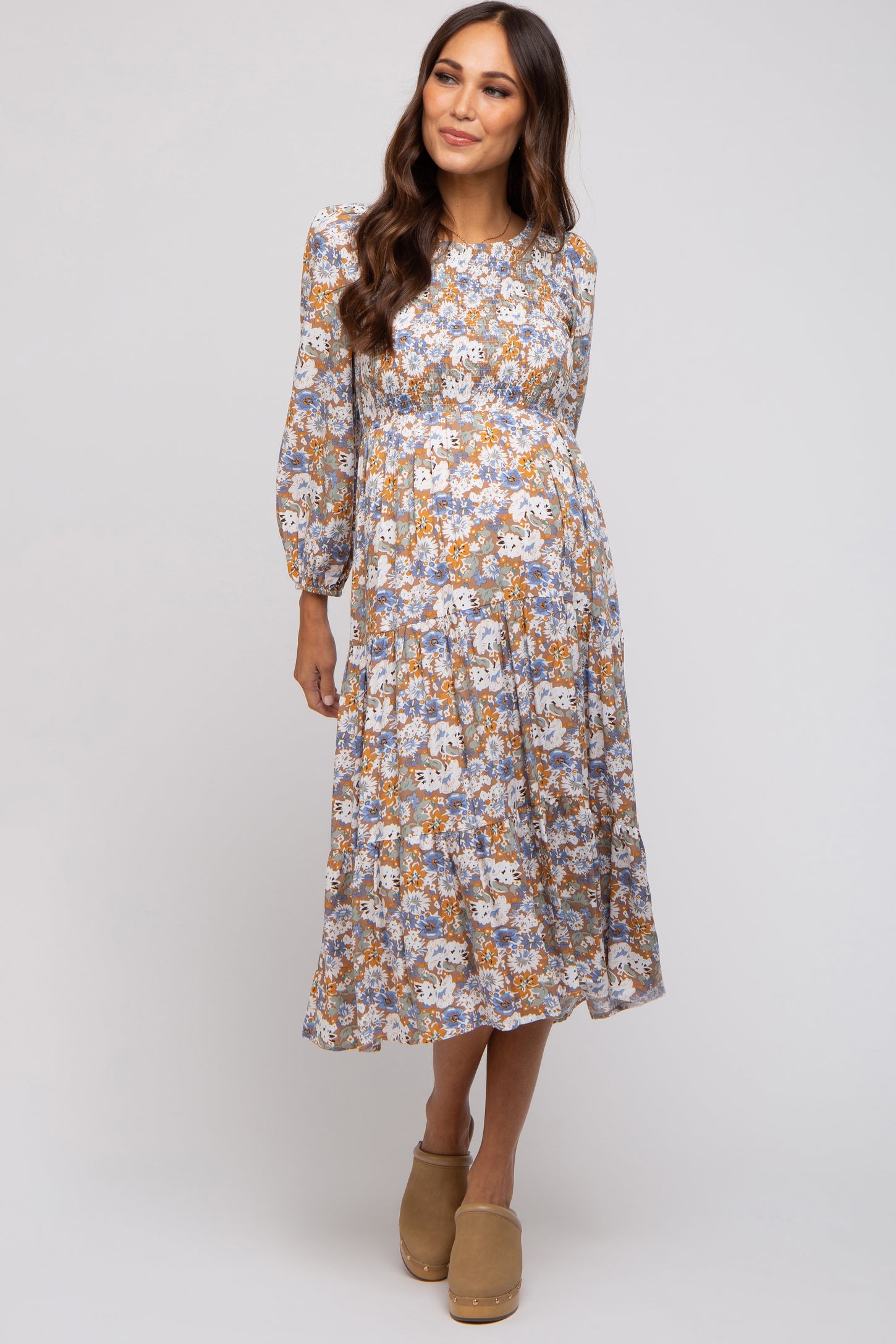 woman wearing a floral patterned maternity dress with long sleeves and a knee-length skirt, showcasing a baby bump