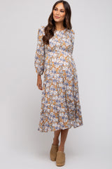 woman wearing a floral patterned maternity dress with long sleeves and a knee-length skirt, showcasing a baby bump