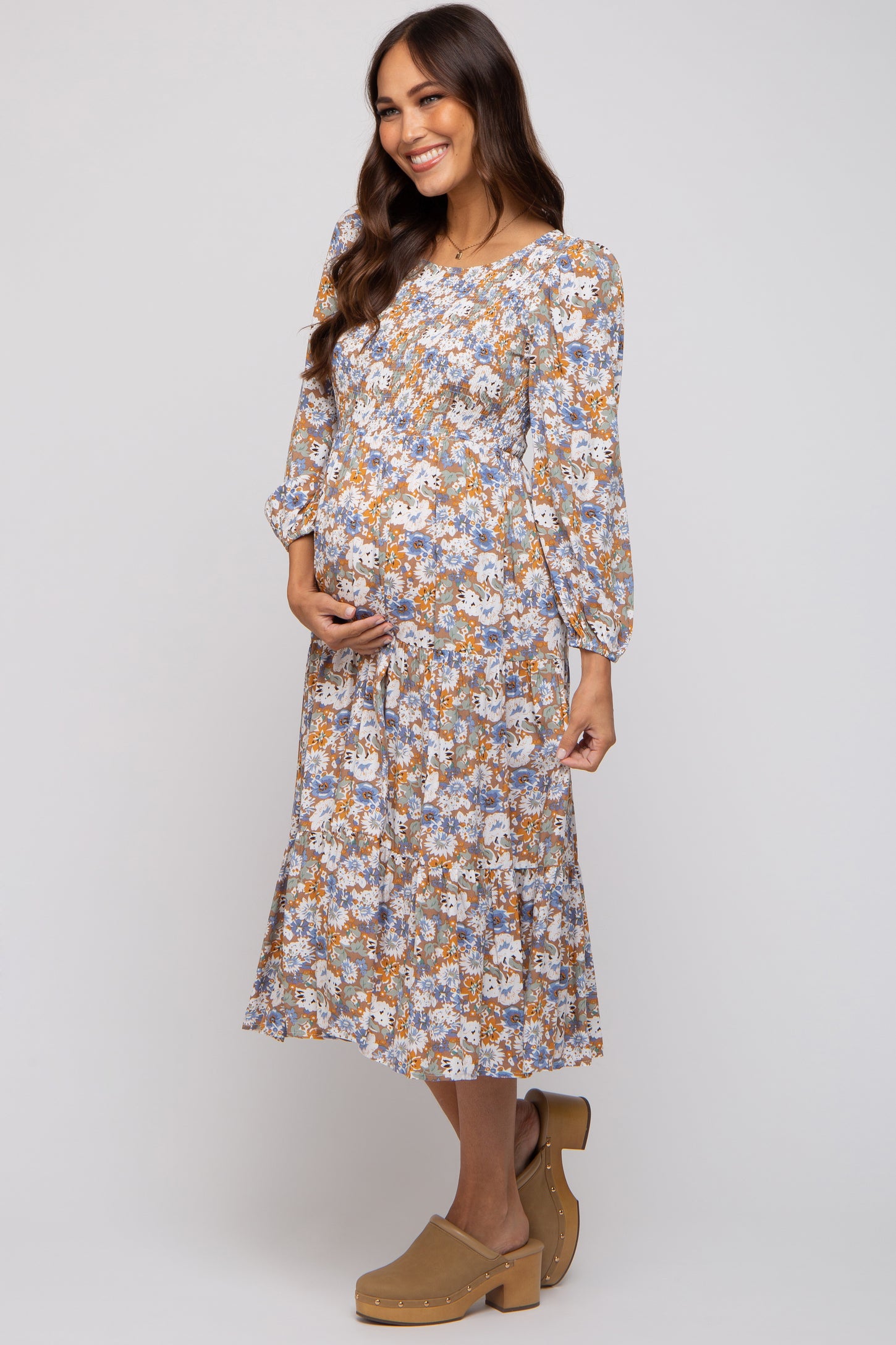 woman wearing a floral long sleeve maternity dress and holding her baby bump