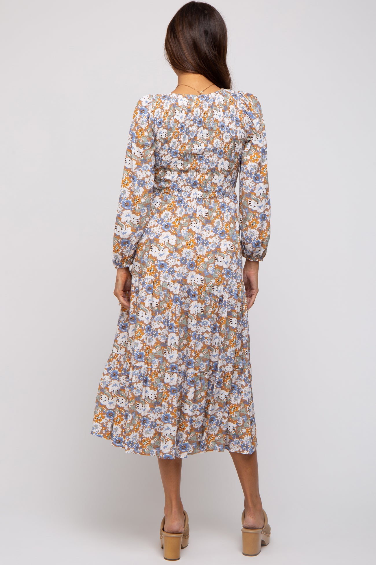 woman wearing a floral long sleeve maternity dress with a tiered skirt and a fitted bodice