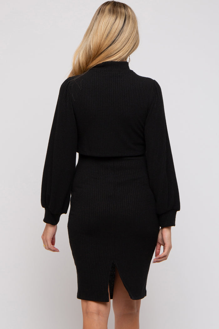 woman wearing a black ribbed maternity dress with long puff sleeves and a back slit detail