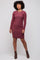 woman wearing a burgundy long sleeve textured dress with a round neckline and fitted style, standing confidently