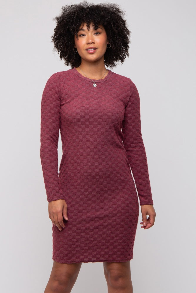 woman wearing a burgundy long sleeve fitted dress with a textured pattern and round neckline