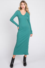 woman wearing a green ribbed long sleeve midi dress with a v-neckline and styled with black ankle boots